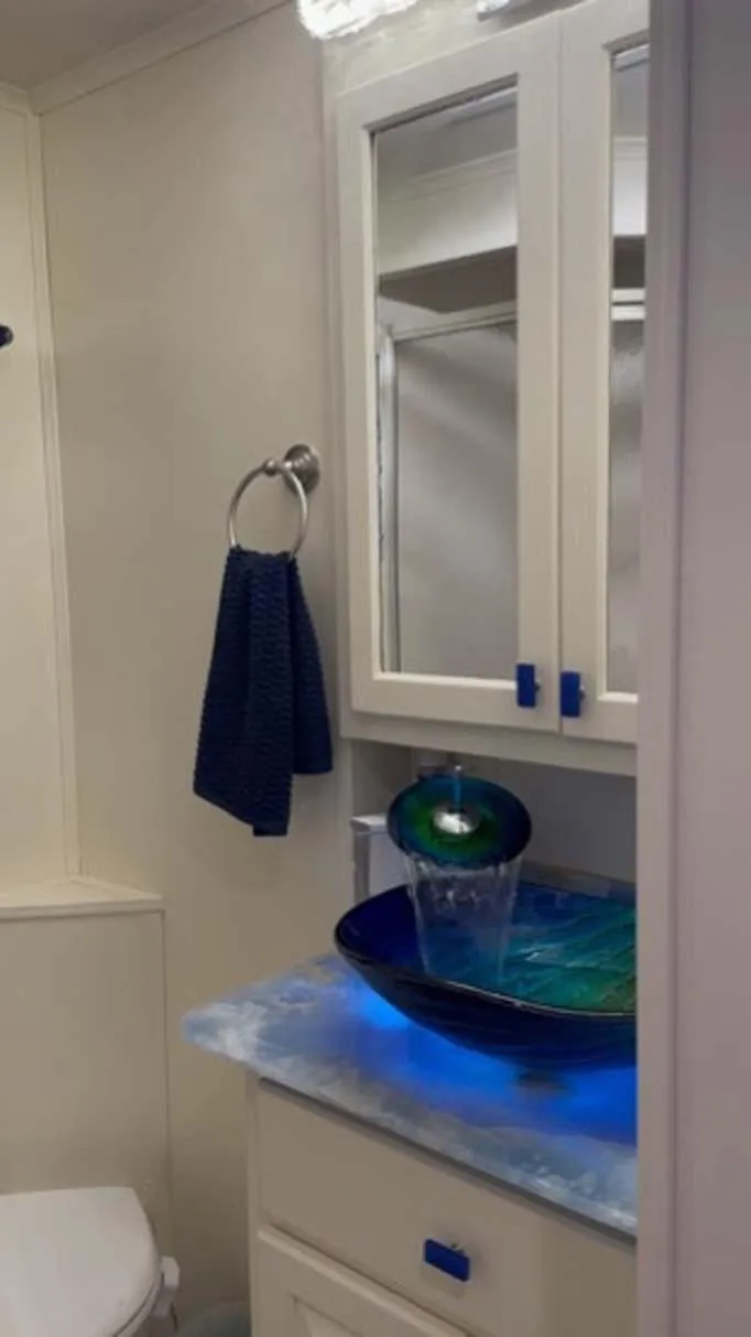 Slide: The Image of Modern bathroom with blue glass sink, illuminated countertop, and mirrored cabinet. Thoroughbred 6516, 2004 model. - 20