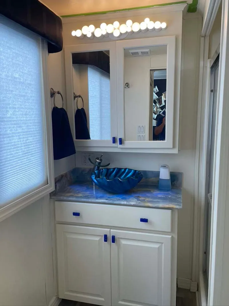 Slide: The Image of Small bathroom with blue glass sink, white cabinets, and bright vanity lighting. - 21