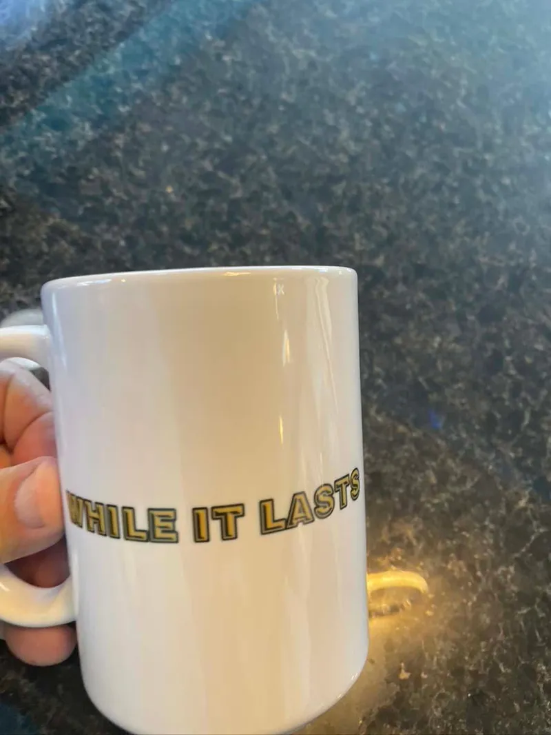 Slide: The Image of White mug with "WHILE IT LASTS" text, held over a dark countertop. - 23