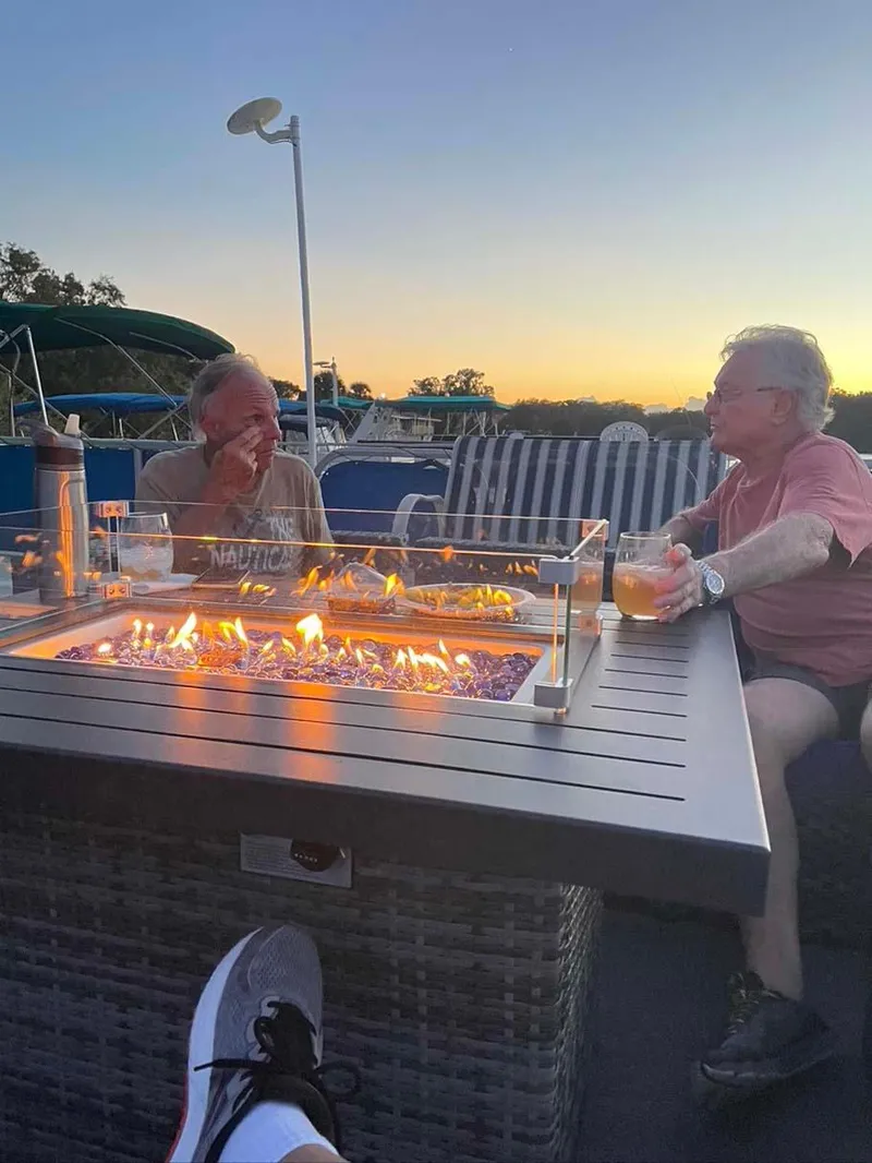 Slide: The Image of Two people relaxing by a fire pit at sunset, enjoying drinks outdoors. - 24