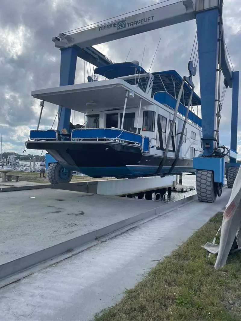 Slide: The Image of A 2004 Thoroughbred 6516 houseboat being lifted by a Marine Travelift at a marina. - 34