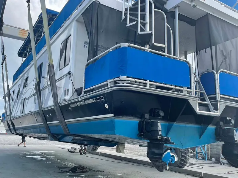 Slide: The Image of 2004 Thoroughbred 6516 houseboat being lifted, showcasing blue and white exterior design. - 36