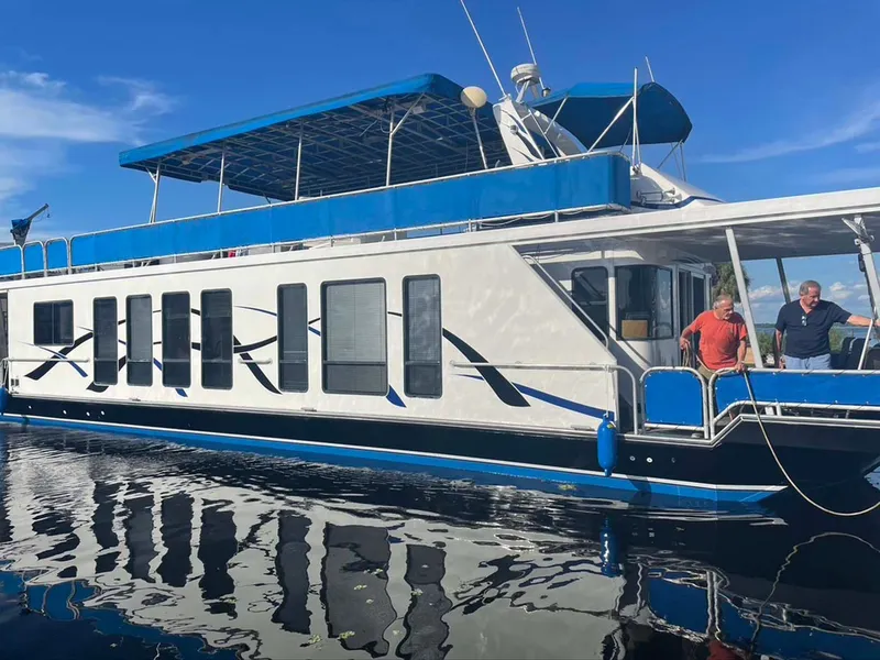 Slide: The Image of 2004 Thoroughbred 6516 houseboat with blue accents on calm water under clear sky. - 38