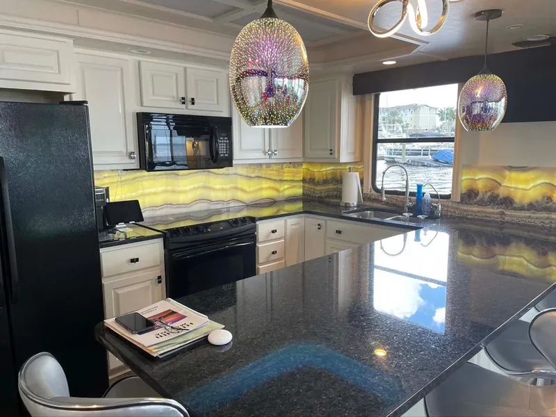 Slide: The Image of Modern kitchen with granite countertops, stylish lighting, and scenic window view in Thoroughbred 6516 model. - 7