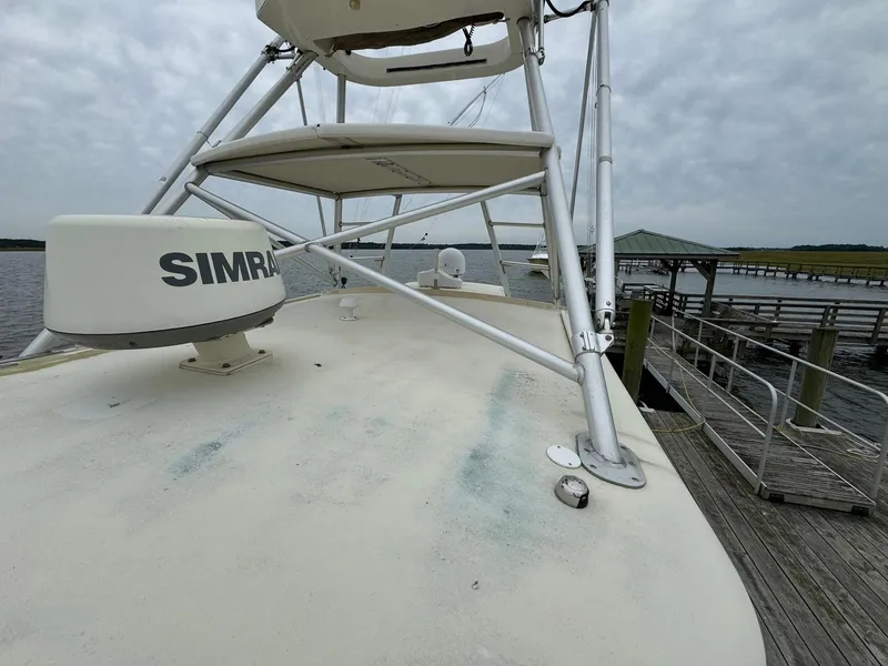 Slide: The Image of 2005 Custom Stardust 32 Express boat docked, featuring Simrad equipment and a cloudy sky backdrop. - 10