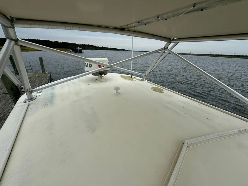 Slide: The Image of 2005 Custom Stardust 32 Express boat deck with canopy, docked by calm waters. - 13