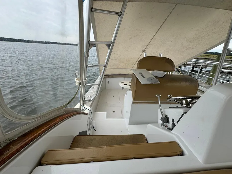 Slide: The Image of 2005 Custom Stardust 32 Express boat interior with seating and helm, docked by the water. - 31
