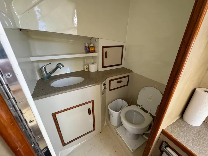 Slide: The Image of Compact bathroom in 2005 Custom Stardust 32 Express boat with sink, toilet, and storage. - 39