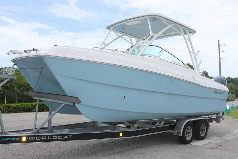 The Image of 2025 World Cat 230 SD boat on trailer, light blue hull, parked outdoors. - 0