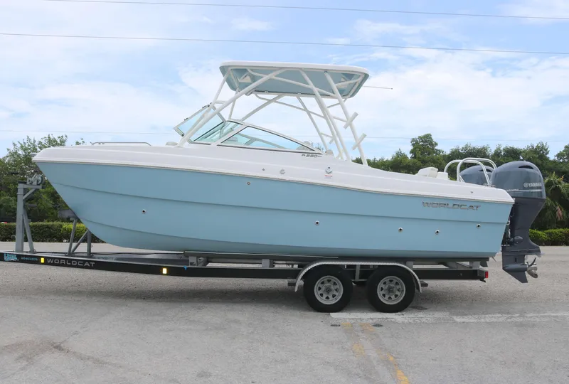 Slide: The Image of 2025 World Cat 230 SD boat on trailer, light blue hull, dual engines. - 1