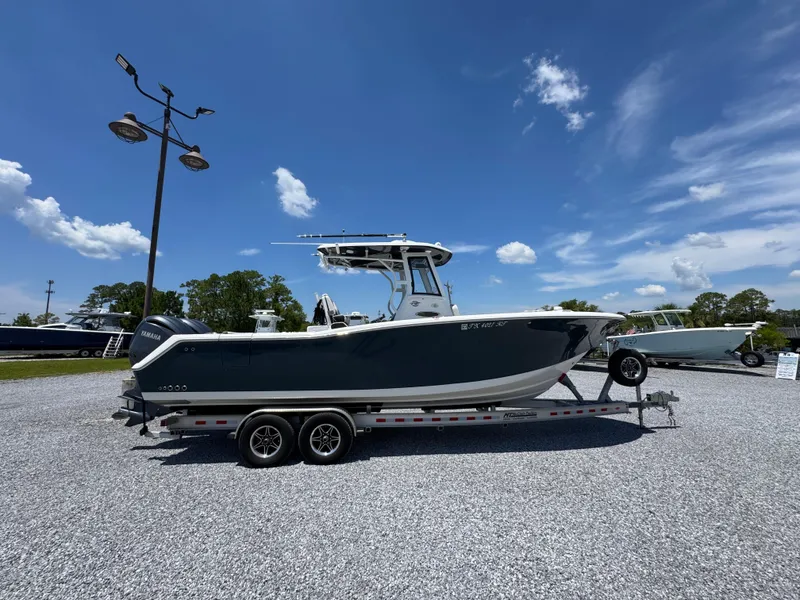The Image of 2023 Tidewater 282 CC Adventure Bluewater boat on trailer under clear blue sky. - 1