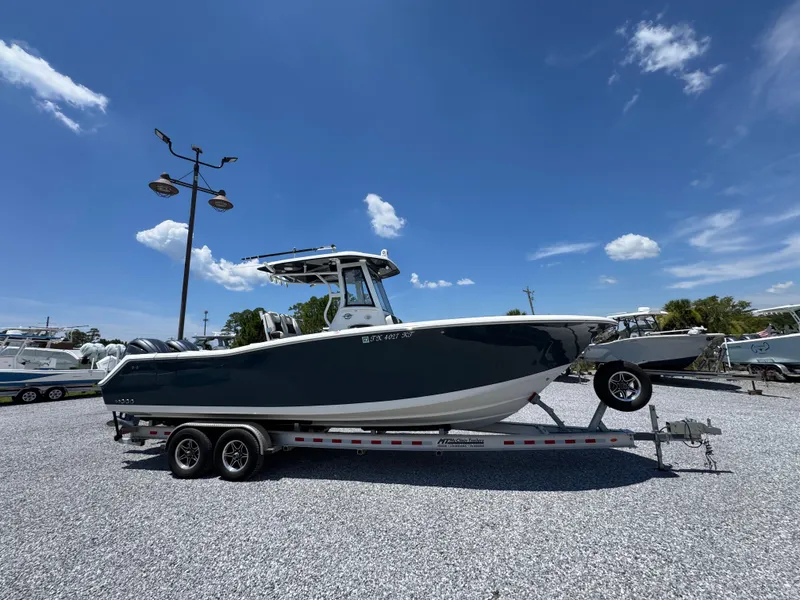 Slide: The Image of 2023 Tidewater 282 CC Adventure Bluewater boat on trailer under clear blue sky. - 2