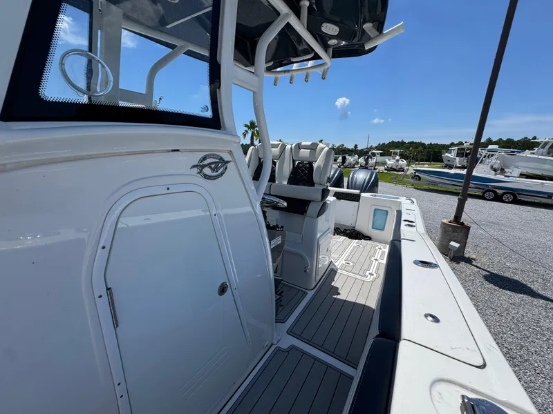 Slide: The Image of 2023 Tidewater 282 CC Adventure Bluewater boat interior with seating and console, under clear blue sky. - 24