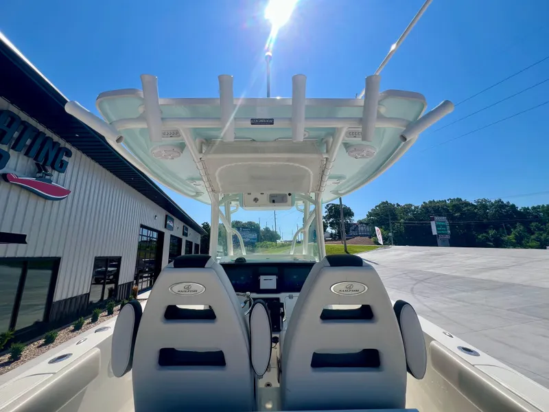 Slide: The Image of 2023 Sailfish 290 CC boat interior with dual seats and overhead canopy in sunny setting. - 11