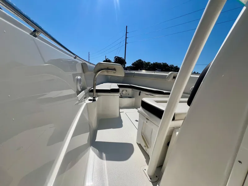 Slide: The Image of 2023 Sailfish 290 CC boat interior with seating and storage under clear blue sky. - 18