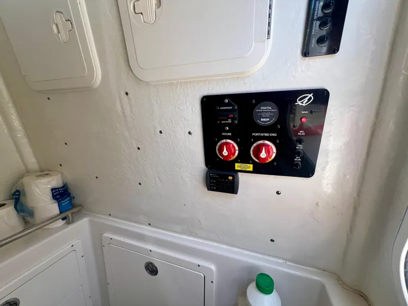 Slide: The Image of Control panel inside 2023 Sailfish 290 CC boat, featuring switches and storage compartments. - 23