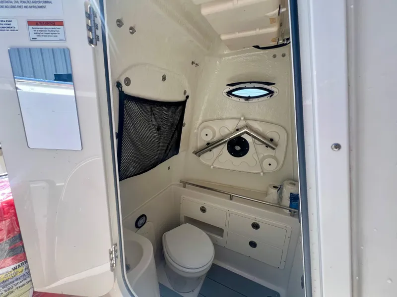 Slide: The Image of 2023 Sailfish 290 CC boat interior with compact bathroom and storage. - 25