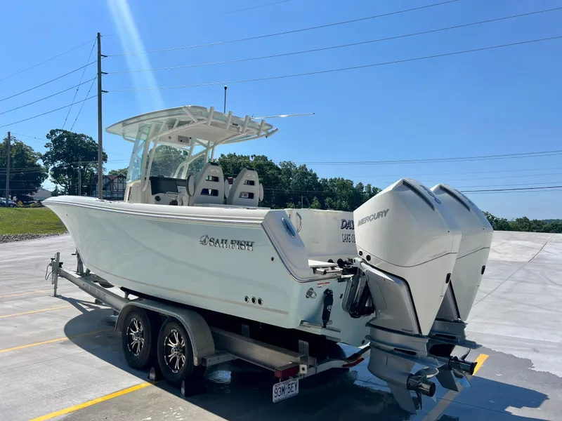 Slide: The Image of 2023 Sailfish 290 CC boat on trailer with dual Mercury engines, parked outdoors. - 4