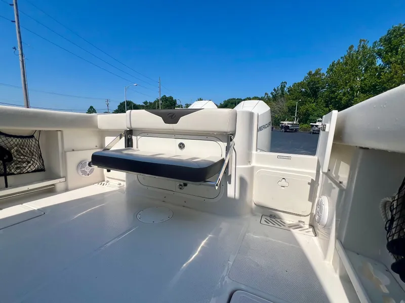 Slide: The Image of 2023 Sailfish 290 CC boat interior with seating and storage, under clear blue sky. - 6