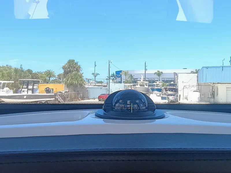 Slide: The Image of 2024 Robalo R250 Center Console boat dashboard with compass, marina view. - 16