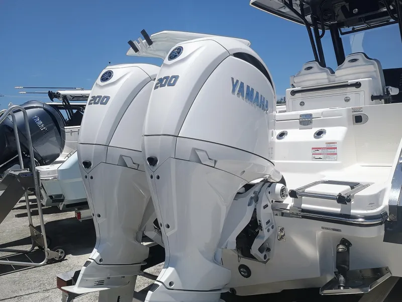 Slide: The Image of 2024 Robalo R250 Center Console with dual Yamaha 200 engines, docked under clear blue sky. - 6
