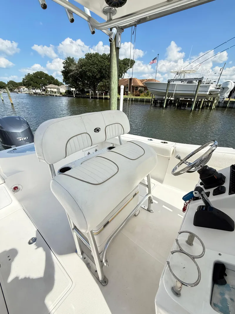 Slide: The Image of 2015 Sea Fox 256 Commander boat interior with helm and seating, docked by the water. - 11
