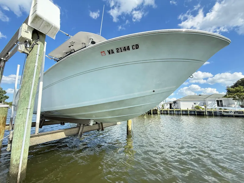 Slide: The Image of 2015 Sea Fox 256 Commander boat on lift, dockside view, under clear blue sky. - 32