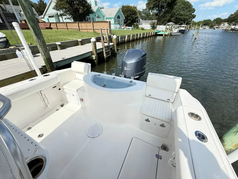 Slide: The Image of 2015 Sea Fox 256 Commander boat interior with seating and motor, docked by a waterfront. - 9