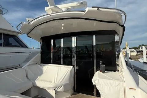 Slide: The Image of 2017 Regal 46 Sport Coupe yacht with white seating and glass doors, docked at a marina. - 20