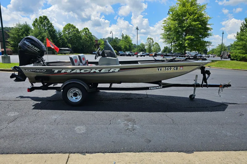 Slide: The Image of 2016 Tracker PRO160 boat on trailer in parking lot, sunny day, trees in background. - 5