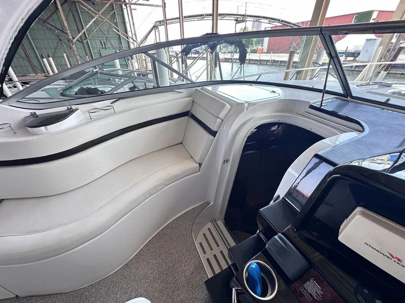 Slide: The Image of 2014 Rinker 310 Express Cruiser interior with white seating and helm, docked in a marina. - 12