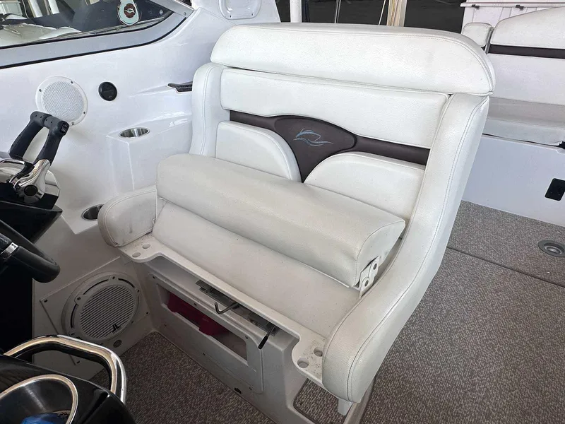 Slide: The Image of 2014 Rinker 310 Express Cruiser helm seat with white upholstery and integrated speaker. - 14