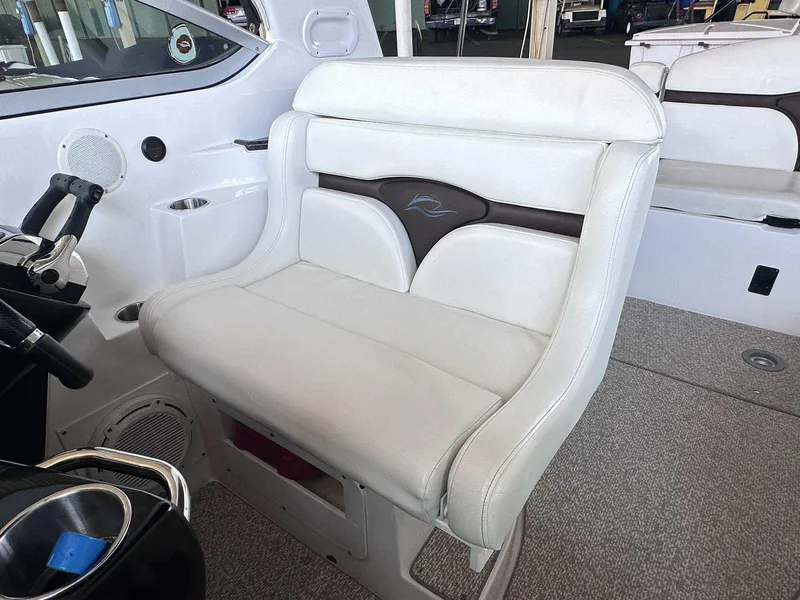 Slide: The Image of 2014 Rinker 310 Express Cruiser helm seat with white upholstery and steering controls. - 15