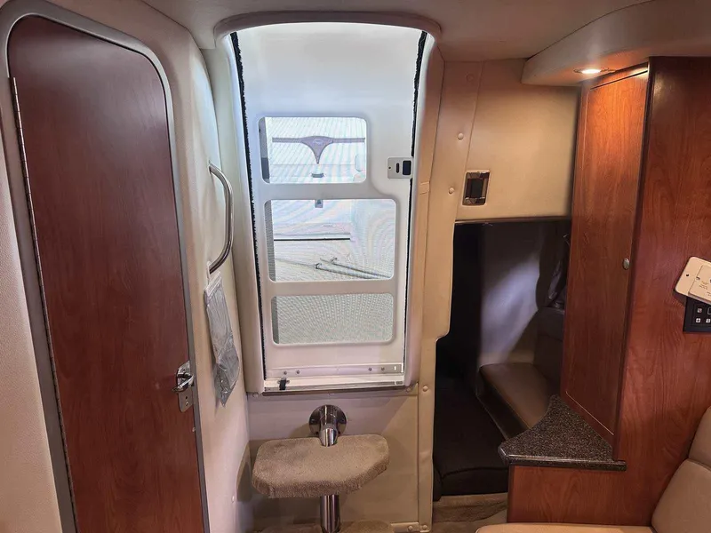 Slide: The Image of 2014 Rinker 310 Express Cruiser interior with kitchenette, TV, and bed. - 26