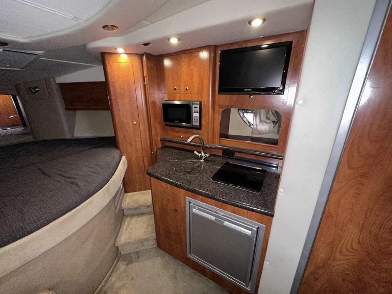 Slide: The Image of 2014 Rinker 310 Express Cruiser interior cabin with wood paneling and storage. - 28