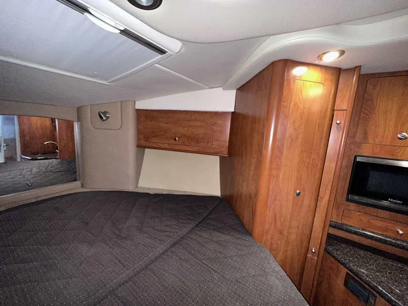 Slide: The Image of 2014 Rinker 310 Express Cruiser interior with beige seating, wood accents, and compact kitchen. - 30