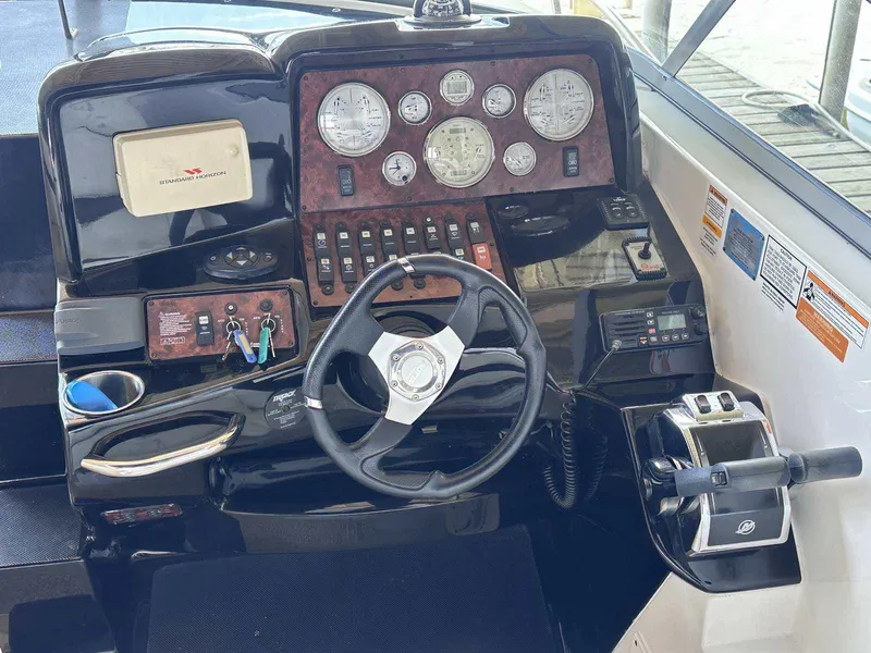 Slide: The Image of 2014 Rinker 310 Express Cruiser helm with steering wheel, gauges, and controls. - 9
