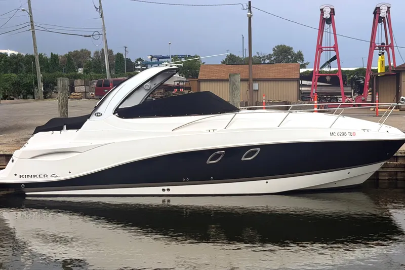 The Image of 2014 Rinker 310 Express Cruiser docked at marina, side view. - 0