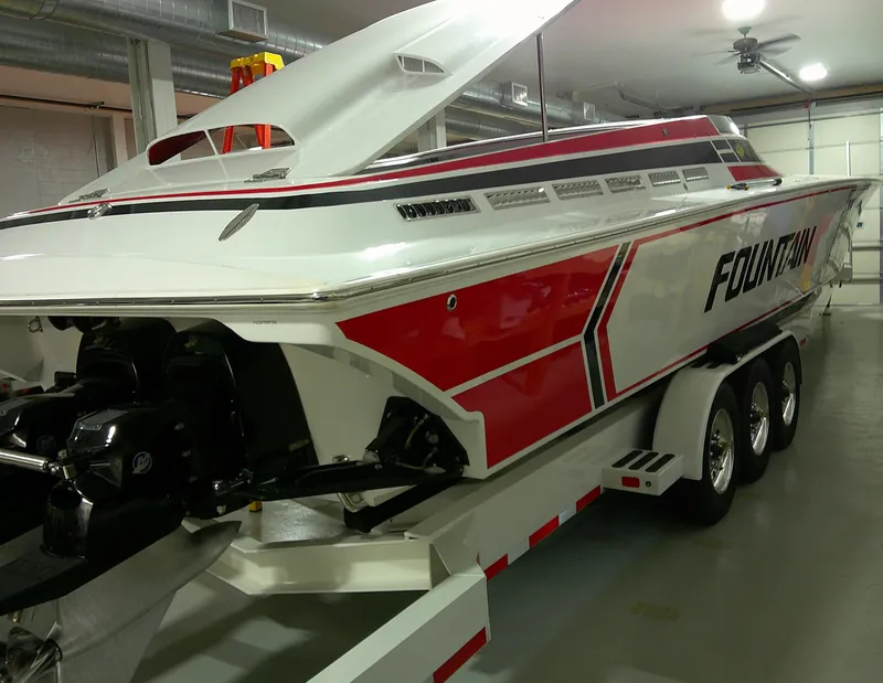 Slide: The Image of 1993 Fountain 47 powerboat on trailer in garage, featuring red and white design. - 9