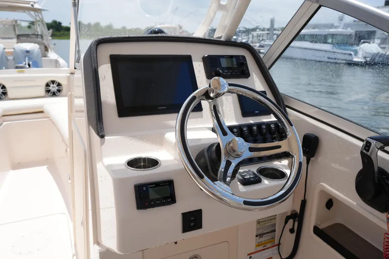 Slide: The Image of 2023 Grady-White Freedom 235 boat helm with steering wheel and navigation screens. - 28