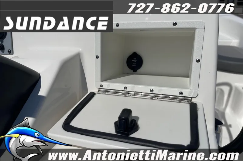 Slide: The Image of Open storage compartment on a 2025 Sundance DX20 boat, featuring auxiliary input. - 30