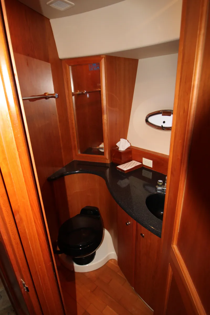 Slide: The Image of 2002 Silverton 43 Motor Yacht bathroom with wood cabinetry and black countertop. - 19