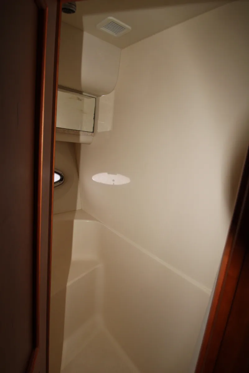 Slide: The Image of Interior of 2002 Silverton 43 Motor Yacht, featuring a compact, beige bathroom space. - 24