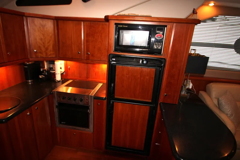 Slide: The Image of 2002 Silverton 43 Motor Yacht kitchen with wood cabinetry, microwave, and stove. - 27