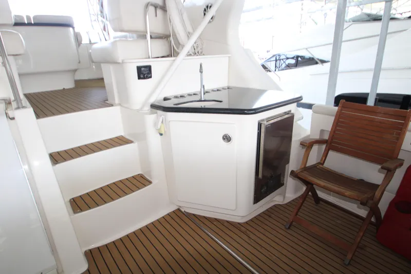 Slide: The Image of 2002 Silverton 43 Motor Yacht interior with wooden flooring, seating, and kitchenette area. - 49