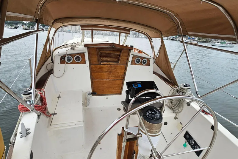 Slide: The Image of 1977 Seafarer 38 sailboat cockpit with wooden accents and steering wheel, docked in marina. - 12