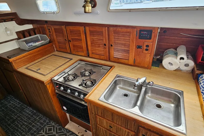 Slide: The Image of 1977 Seafarer 38 yacht kitchen with stove, double sink, and wooden cabinets. - 13