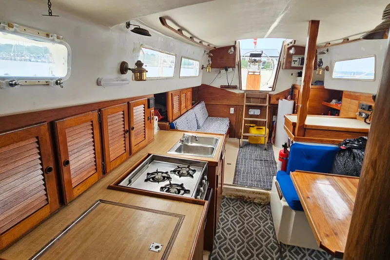 Slide: The Image of 1977 Seafarer 38 yacht interior with wooden cabinetry, stove, and seating area. - 18
