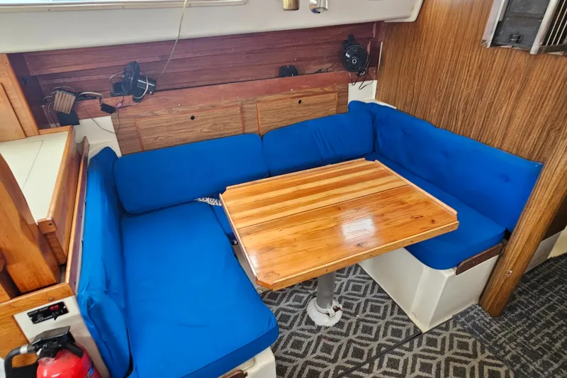 Slide: The Image of 1977 Seafarer 38 interior with blue cushioned seating and wooden table. - 19