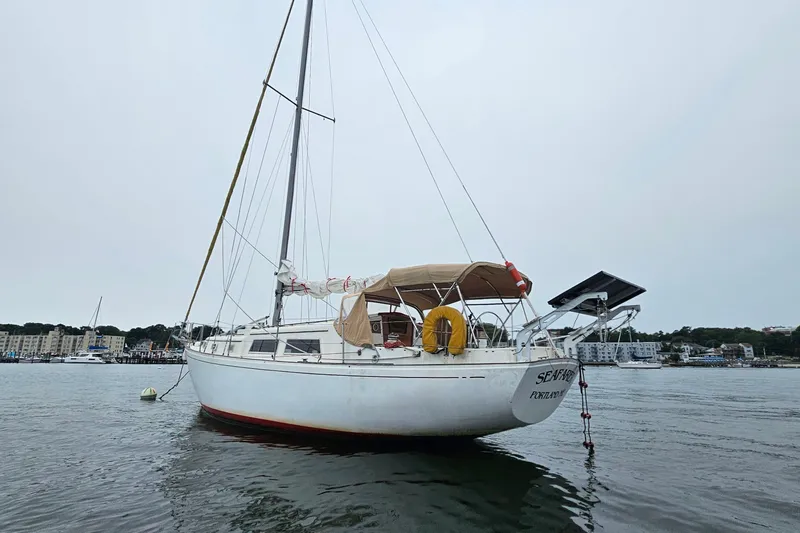 Slide: The Image of 1977 Seafarer 38 sailboat anchored in calm waters, featuring a beige canopy. - 9